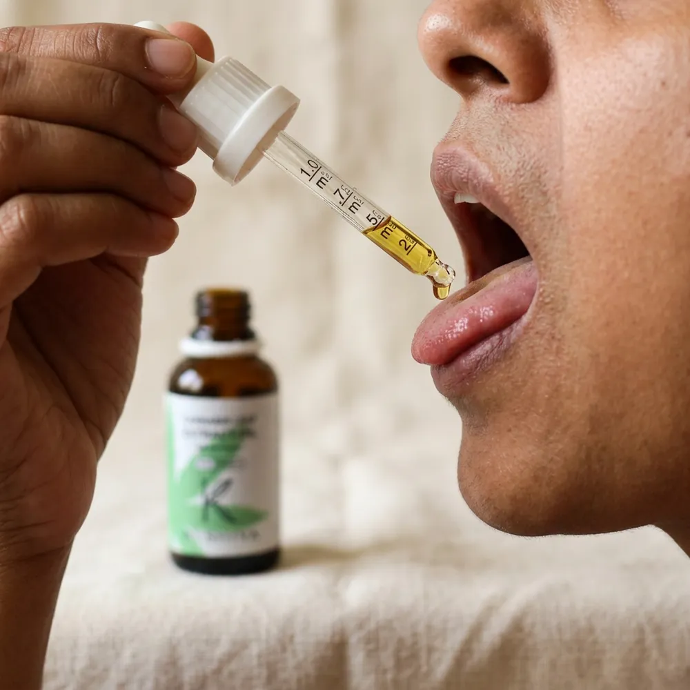 Hand using a Kushiva cannabis leaf extract oil dropper for sublingual dosing