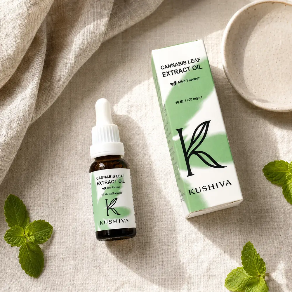 Kushiva Cannabis Leaf Extract Oil 10 ml bottle beside its mint-flavour carton, flat lay with fresh mint